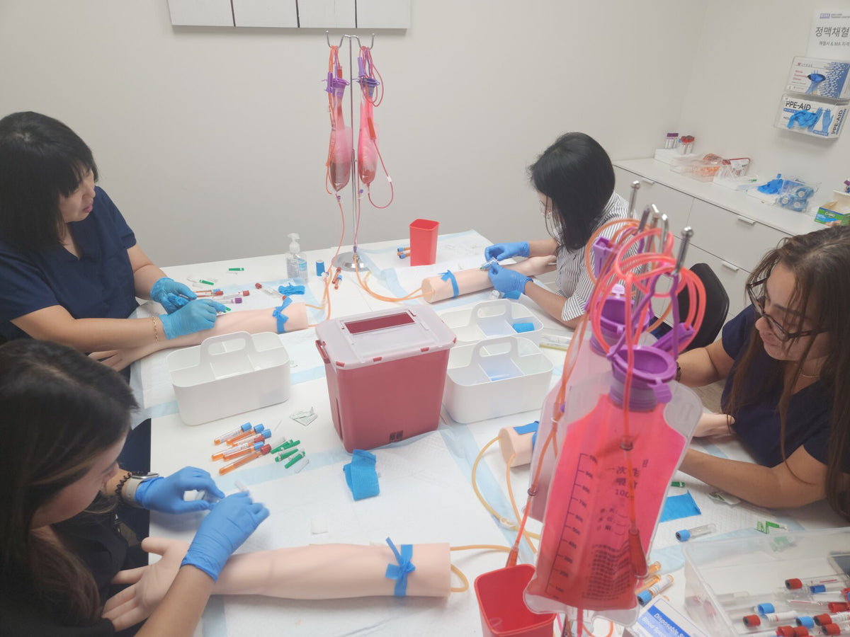 DMS students practicing phlebotomy skills on training arms in the skills lab.